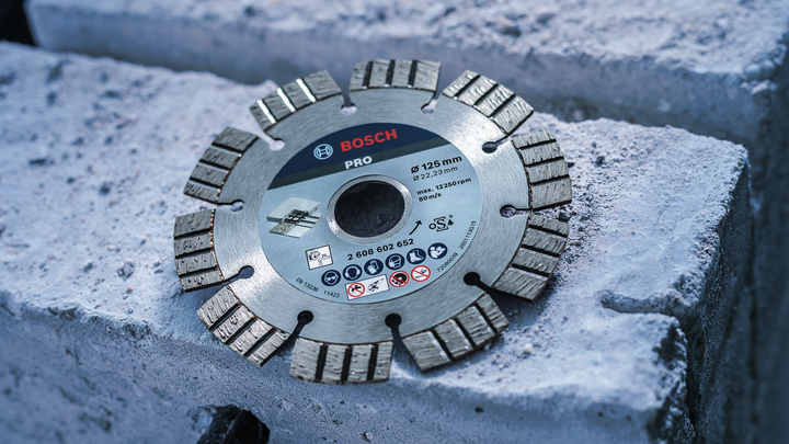 Segmented diamond saw blade resting on concrete blocks.