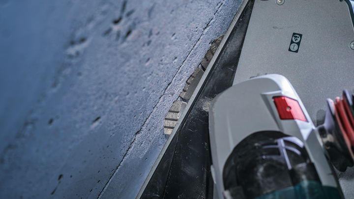 Angle grinder with a diamond blade cuts into a concrete surface.