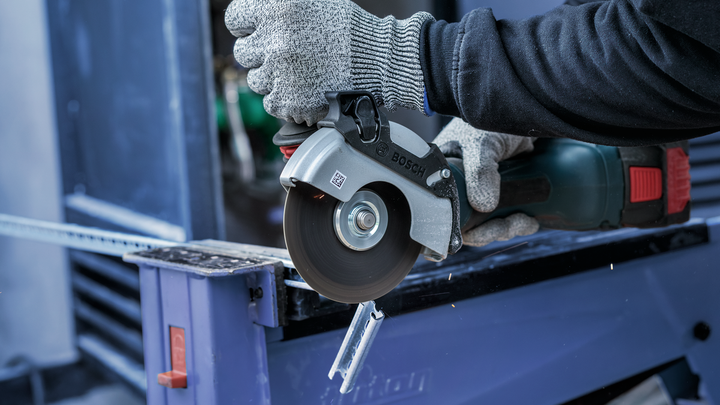 Person wearing safety equipment uses a circular saw to cut a metal channel.