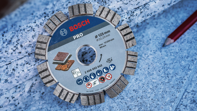 Segmented diamond cutting disc placed on a granite slab beside a red pencil.