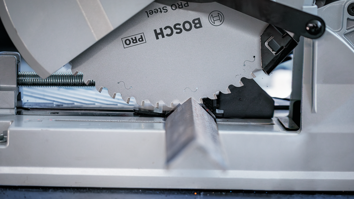 Circular saw blade cutting through a metal beam at an angle.
