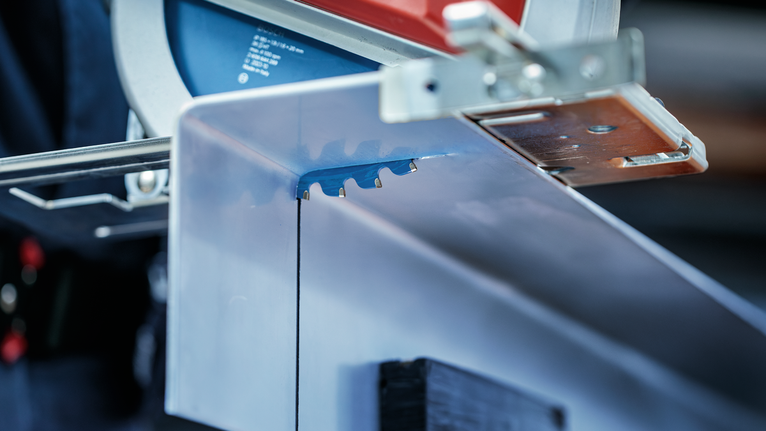 Circular saw blade cutting through a sheet of metal.