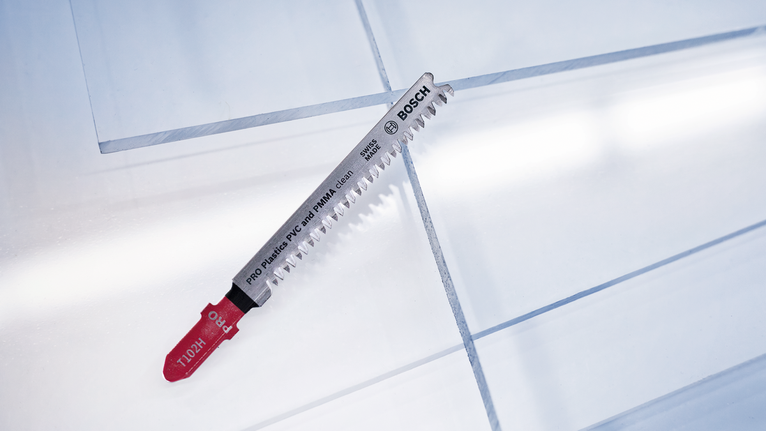 Jigsaw blade placed on top of transparent plastic sheets.