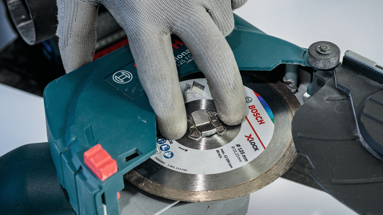 Person wearing safety equipment adjusts a circular saw blade.