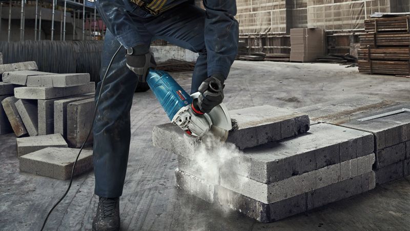 A person wearing safety equipment cuts concrete blocks with a power cutter.