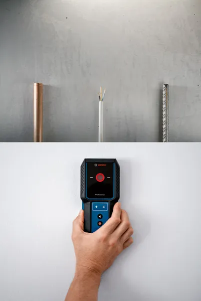 Person uses a detector on a wall to locate pipe, wire, and rebar behind the surface.