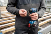 A person inserts a drill bit into a cordless screwdriver at a construction site.