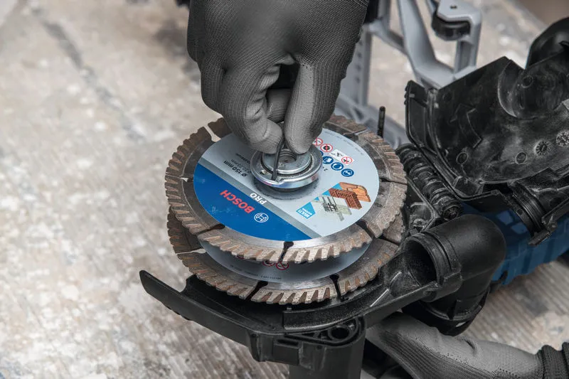 A person wearing safety equipment installs a cutting disc on a wall chaser.