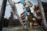A worker wearing safety equipment uses a rotary hammer to drill into a concrete base at a construction site.