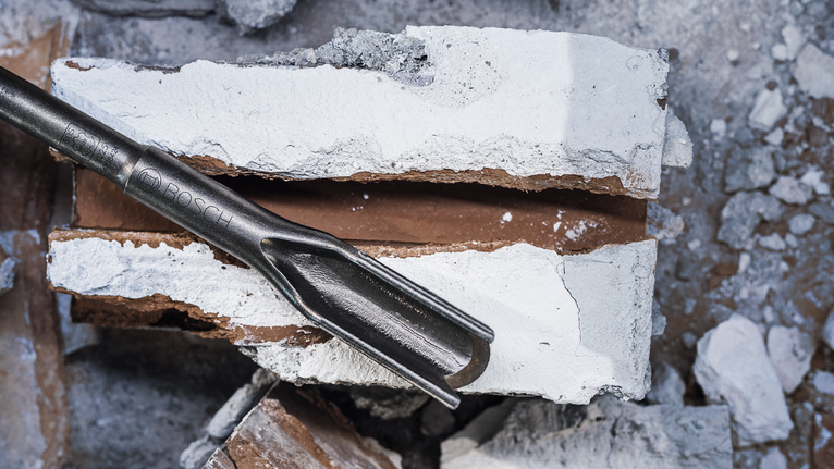 Chisel tool breaking through a concrete block.