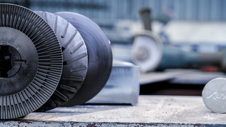 Close-up of metal grinding discs resting on a workbench in an industrial setting.