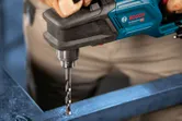 A person drills into metal with a cordless angle drill.
