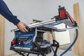 A person adjusts a table saw in a workshop.