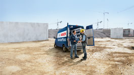 Два человека обсуждают инструменты возле фургона Bosch на строительной площадке.