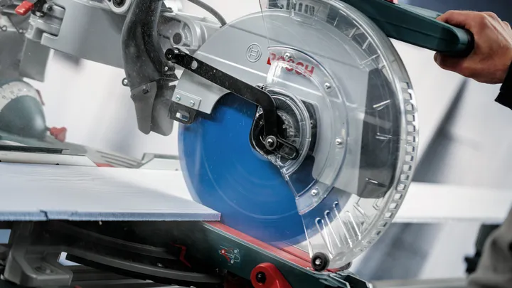 Человек управляет циркулярной пилой, делая точный надрез на большой плитке.