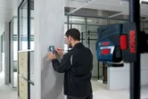 يستخدم الشخص جهاز استقبال ليزر لرسم خط مرجعي على عمود خرساني.