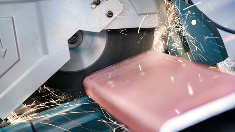 تتطاير الشرر عندما يقطع شفرة المنشار المقطع قضيبًا معدنيًا.