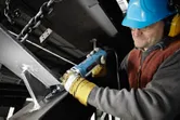 A person wearing safety equipment uses a straight grinder on a steel beam.