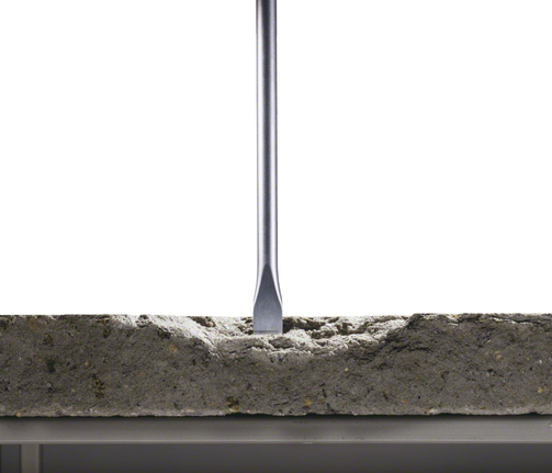 Flat chisel bit breaking into a concrete slab.