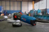 Electric angle grinder with a dust filter attachment resting on a workbench in a workshop.