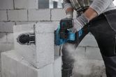 A person wearing safety equipment cuts an AAC block using a power cutter.