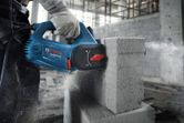 A person wearing safety equipment cuts an AAC block using a blue power cutter.