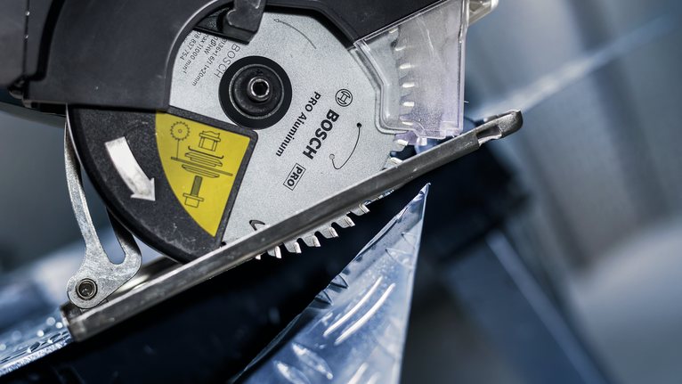 Circular saw blade cutting through a sheet of metal.