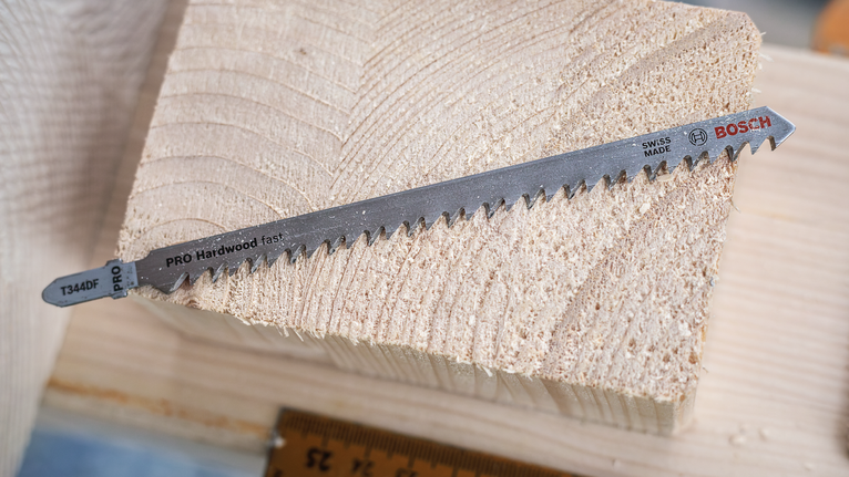 Jigsaw blade resting on a block of cut wood.