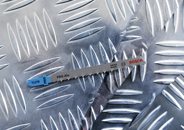 Jigsaw blade on a diamond-patterned metal sheet.