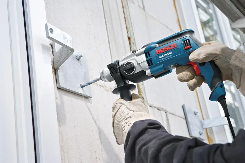 Electric impact drill with side handle attached, featuring a blue and silver casing.