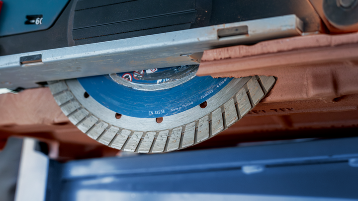 Deimantinis pjūklo diskas pjauna rudą plytą.