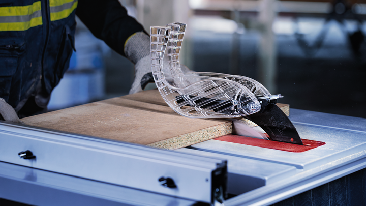 Persona drošības aprīkojumā vada koku caur galda zāģi darbnīcā.