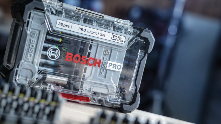 Caurspīdīgs plastmasas korpuss ar dažādiem skrūvgriežu uzgaļiem uz koka virsmas.