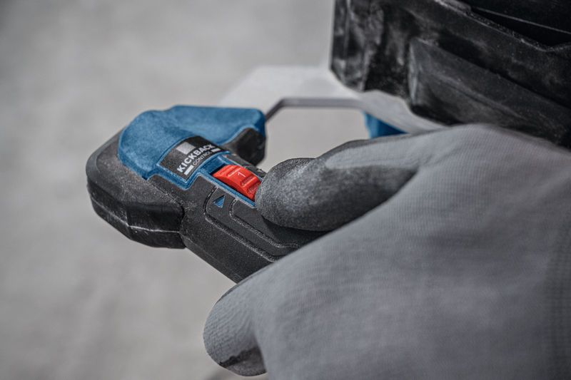 Persona, kas valkā drošības aprīkojumu, darbina maisīšanas mehānismu ar sarkanu vadības slēdzi.