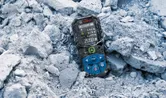 Laser measure resting on broken concrete rubble at a worksite.