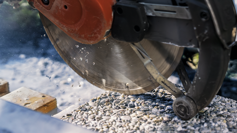 Circular saw cutting through concrete with water spraying.