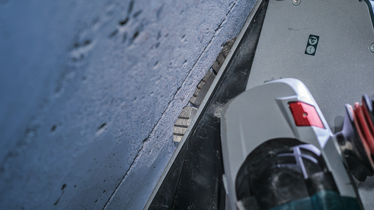 Angle grinder with a diamond blade cuts into a concrete surface.