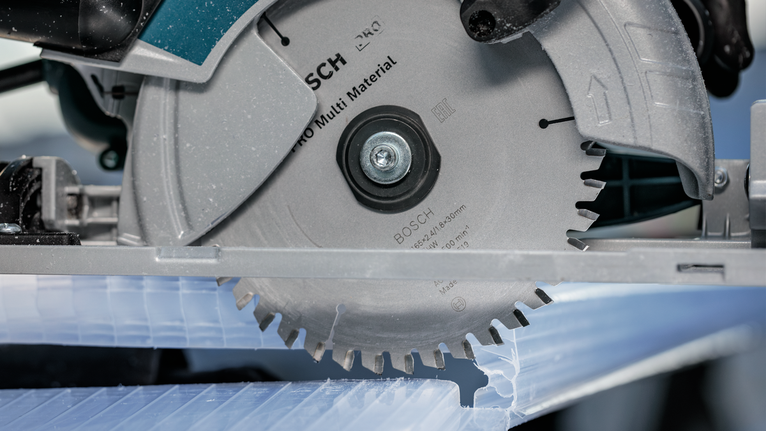 Circular saw cutting through a plastic sheet.