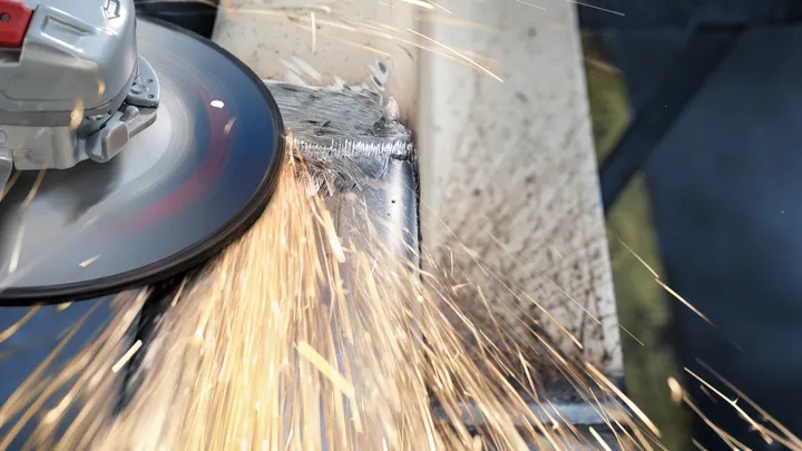 Angle grinder producing sparks as it grinds a metal corner.