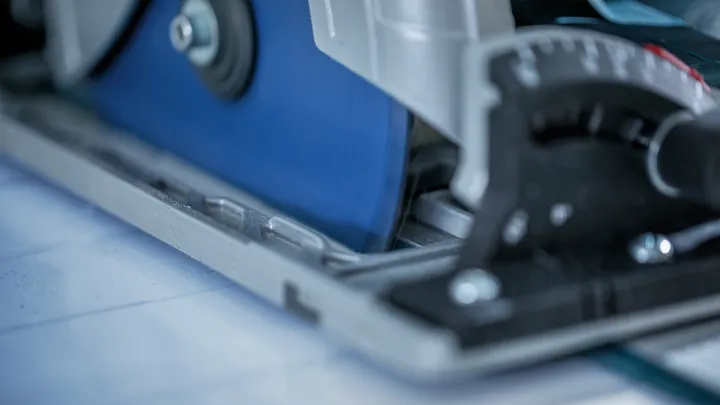 Circular saw blade slicing through tile, with angle adjustment dial in the foreground.