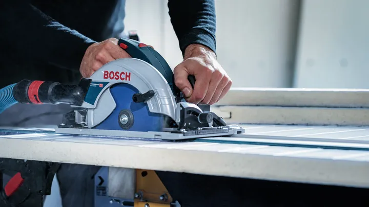 Person uses a circular saw to cut a large tile on a workbench.