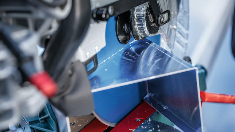 A circular saw cuts through a sheet of metal on a workbench.