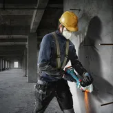 Une personne portant un équipement de sécurité coupe du béton avec une meuleuse d'angle.