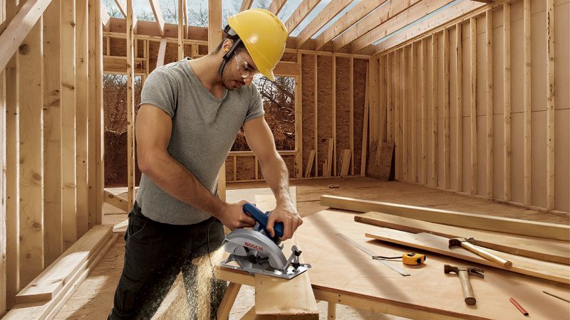 Homme sciant une construction en bois.
