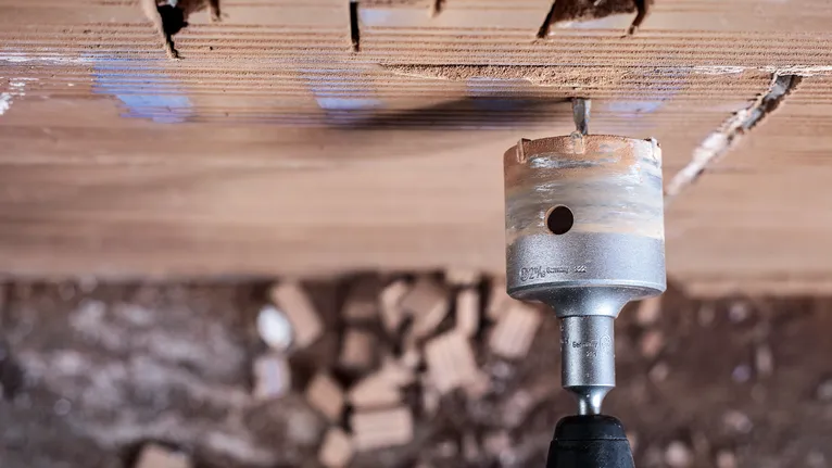 Perçage à la scie cloche dans un mur de briques pendant la construction.