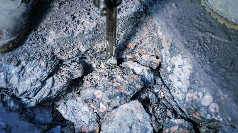 Marteau de démolition brisant le béton en gros morceaux de gravats.