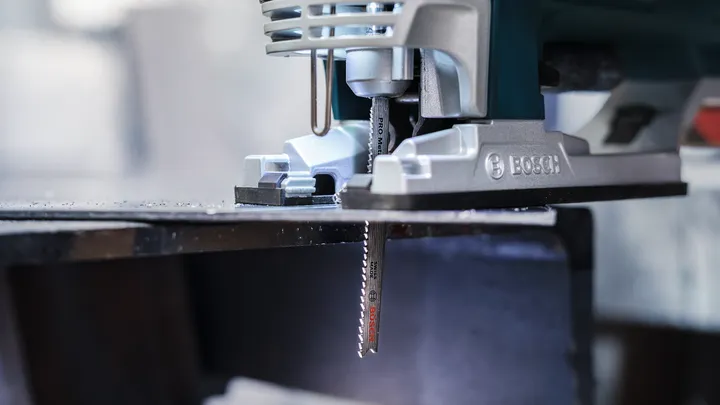 Découpe à la scie sauteuse d'une tôle dans un atelier.