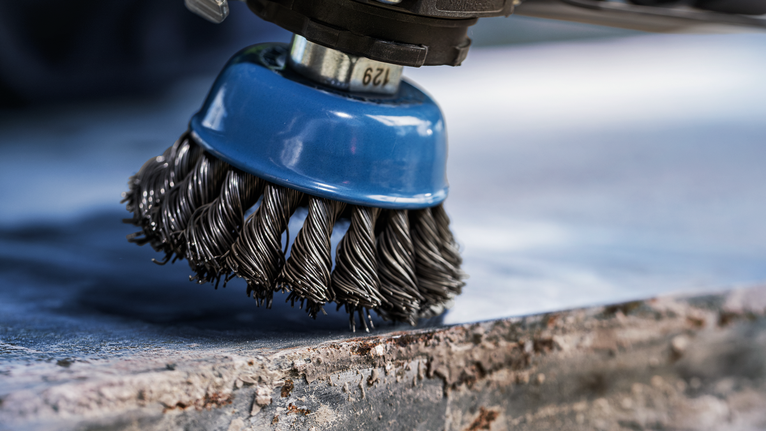Brosse métallique pour éliminer la rouille d'une surface métallique.