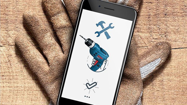 A smartphone shows a blue Bosch cordless screwdriver on gloves.