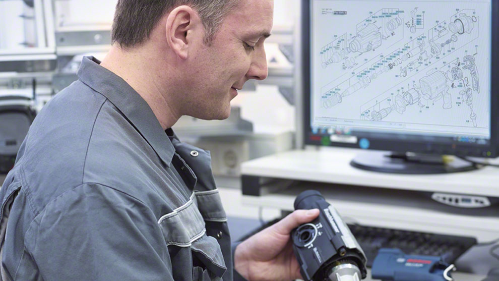 A man in work clothes is looking at a Bosch Professional tool.
